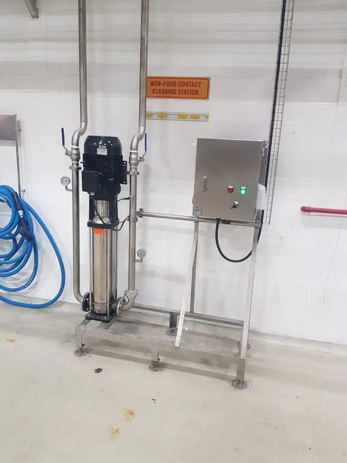 High pressure wash pump installed on a stainless steel frame with its electrical control panel